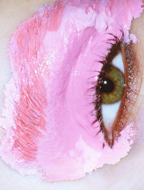Close-up of a human eye surrounded by textured pink paint, showcasing a vibrant and artistic beauty or makeup concept.