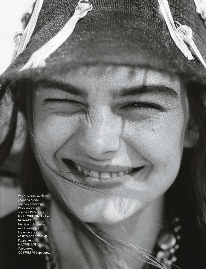 Close-up portrait of a smiling woman wearing a hat with tassels, black and white fashion editorial style shot for a magazine.