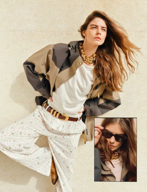 A woman poses in a patterned jacket, white shirt, floral pants, and brown boots with a beige backdrop and inset image.