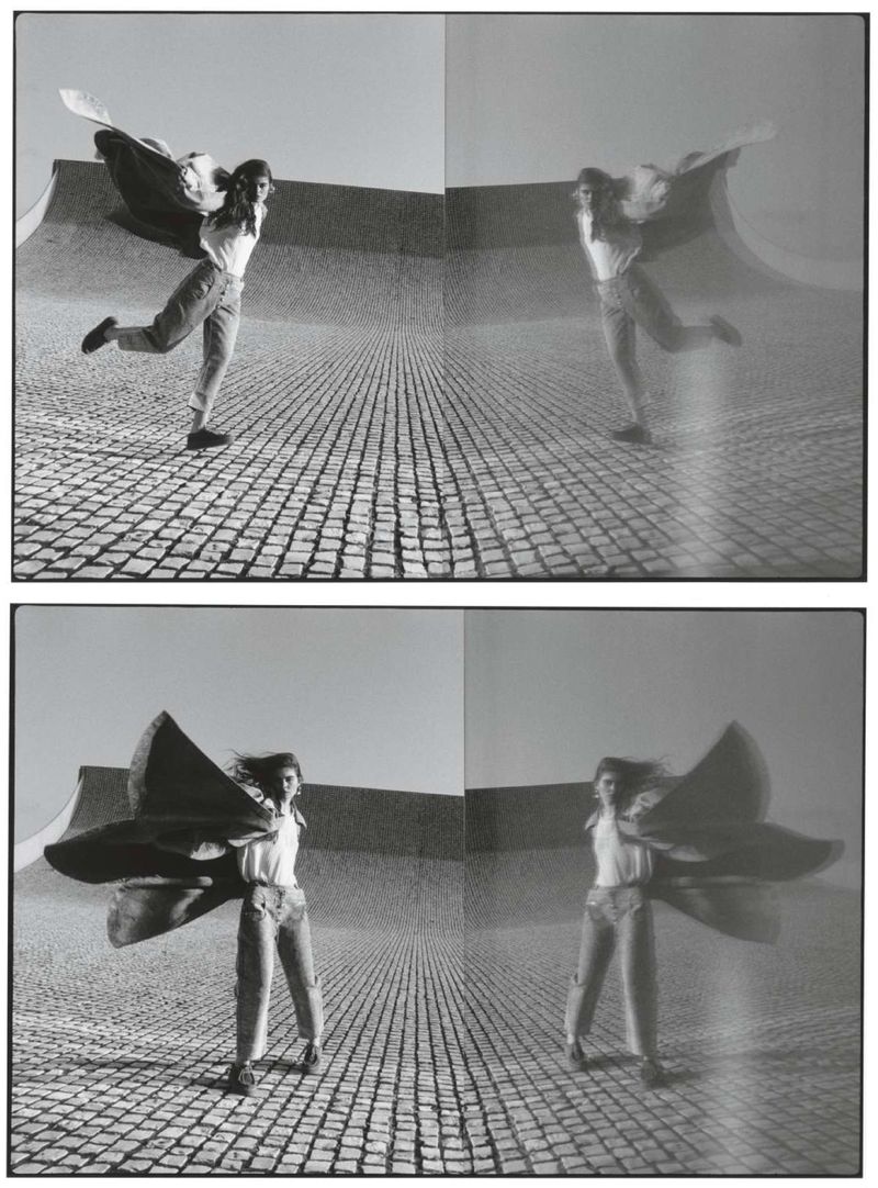 Monochrome studio shot: woman poses outdoors with large flowing cape, reflected multiple times in the background, creating a surreal effect.