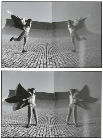 Monochrome studio shot: woman poses outdoors with large flowing cape, reflected multiple times in the background, creating a surreal effect.