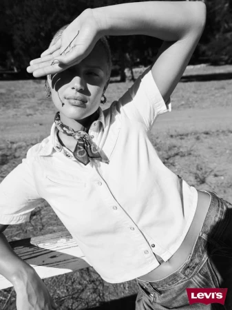 Black and white shot of a fair-skinned adult woman with short hair wearing a button-down shirt and bandana in an outdoor setting.
