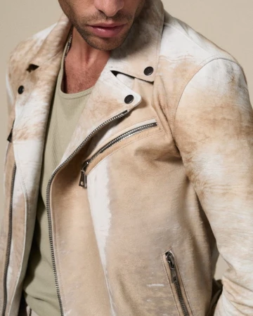 Close-up studio shot of an adult male wearing a weathered beige and white leather biker jacket and light green t-shirt.