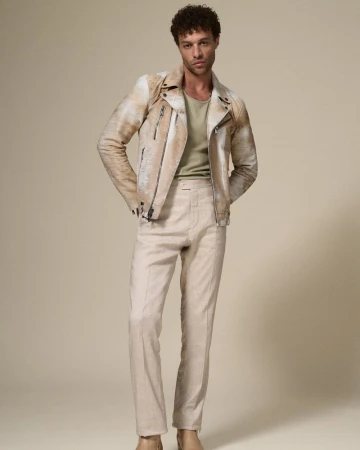 Full-length studio shot of an adult male wearing a light tan leather jacket and matching trousers, posing in front of a neutral backdrop.