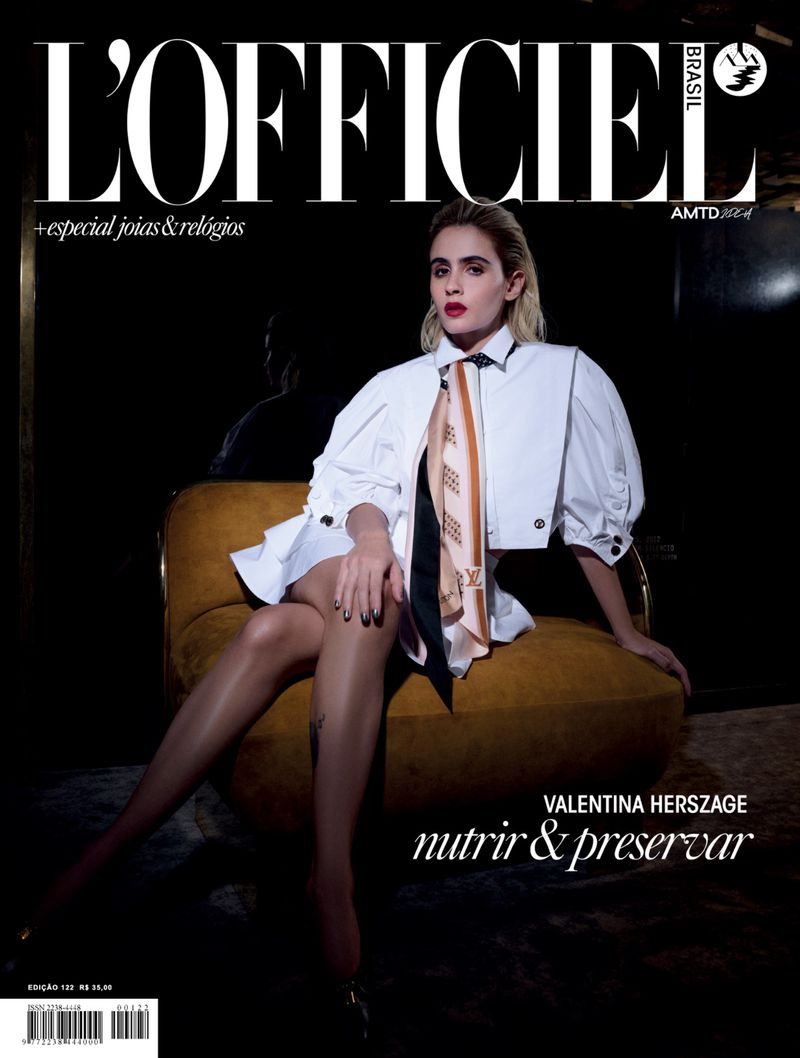Magazine cover featuring a young woman in a white dress, tan stockings, and black shoes, sitting in a mustard yellow chair.