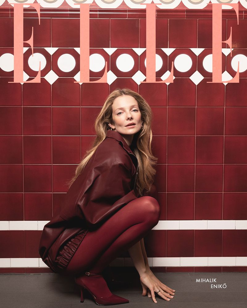 Elle magazine cover featuring a blonde woman in a red outfit squatting against a red tiled wall with white accents. Elle logo visible.
