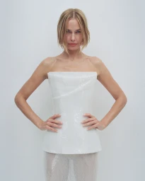 Model with blonde bob wearing a structured white strapless top against a plain light background