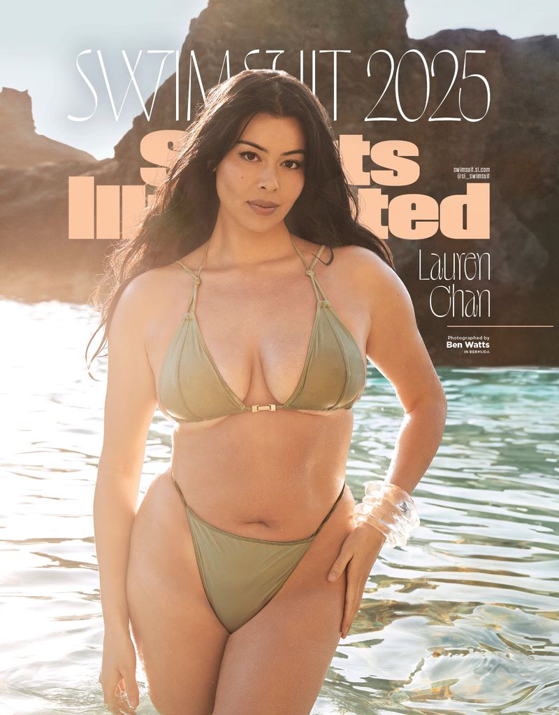 A woman poses in an olive-green bikini in shallow water on a magazine cover with large titles, set against a rocky coastline.