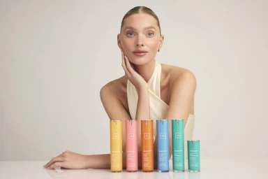 Model Elsa Hosk posing behind six colorful skincare bottles for SunsolveMD, photographed by David Roemer.