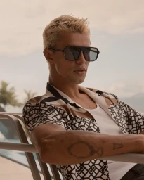 Blonde man wearing sunglasses and patterned shirt seated outdoors for Calibre campaign