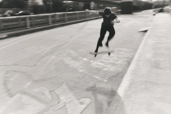 Skateboarder performing an aerial trick on a ramp in a black and white action shot in an urban environment with blurred motion.