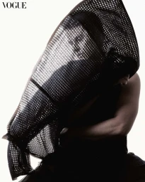 Model wearing a black mesh hooded garment against a bright white background for Vogue Philippines