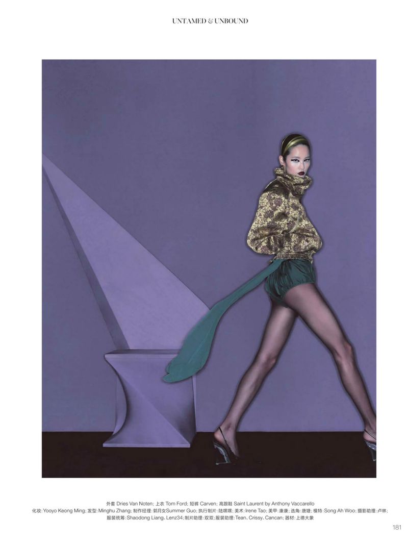 Fashion editorial shot featuring a woman in green shorts and a patterned jacket, walking in a studio with a purple geometric sculpture.