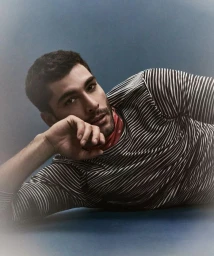Model Paolo Busti reclining in a black and white striped long-sleeve top with a red neck scarf for Le Mile Magazine.