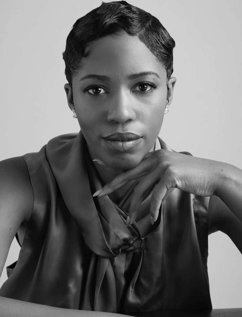 Monochrome portrait of a stylish black woman with finger waves, elegant sleeveless top, and neutral backdrop.