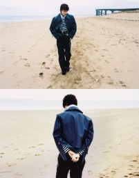 Model wearing a dark jacket and striped top standing on a sandy beach for Annabelle Magazine