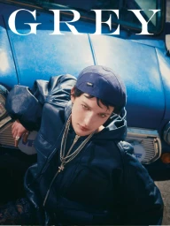 Model wearing a dark blue leather jacket and cap leaning against a vintage blue car for Grey Magazine Italy
