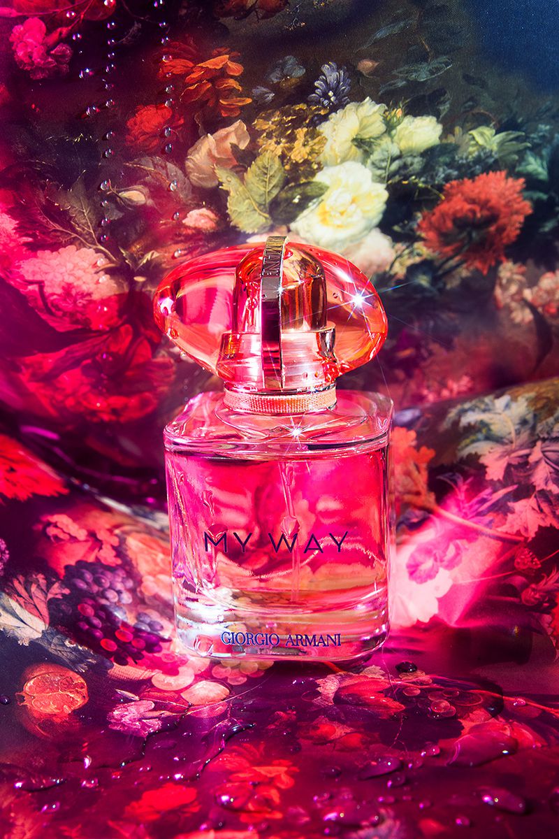 Still life shot of a Giorgio Armani 'My Way' perfume bottle. The bottle is set against a backdrop of vibrant floral patterns.