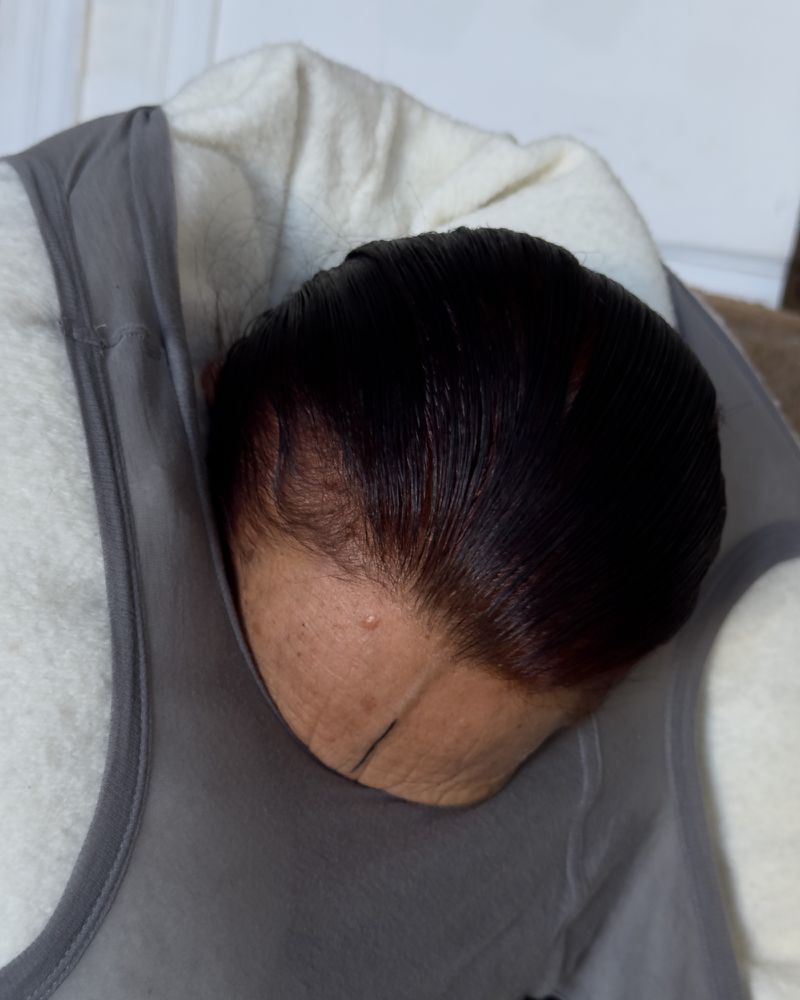 An adult rests with dark hair visible. The subject appears to be relaxing against a fleece garment and gray shirt in an indoor setting.