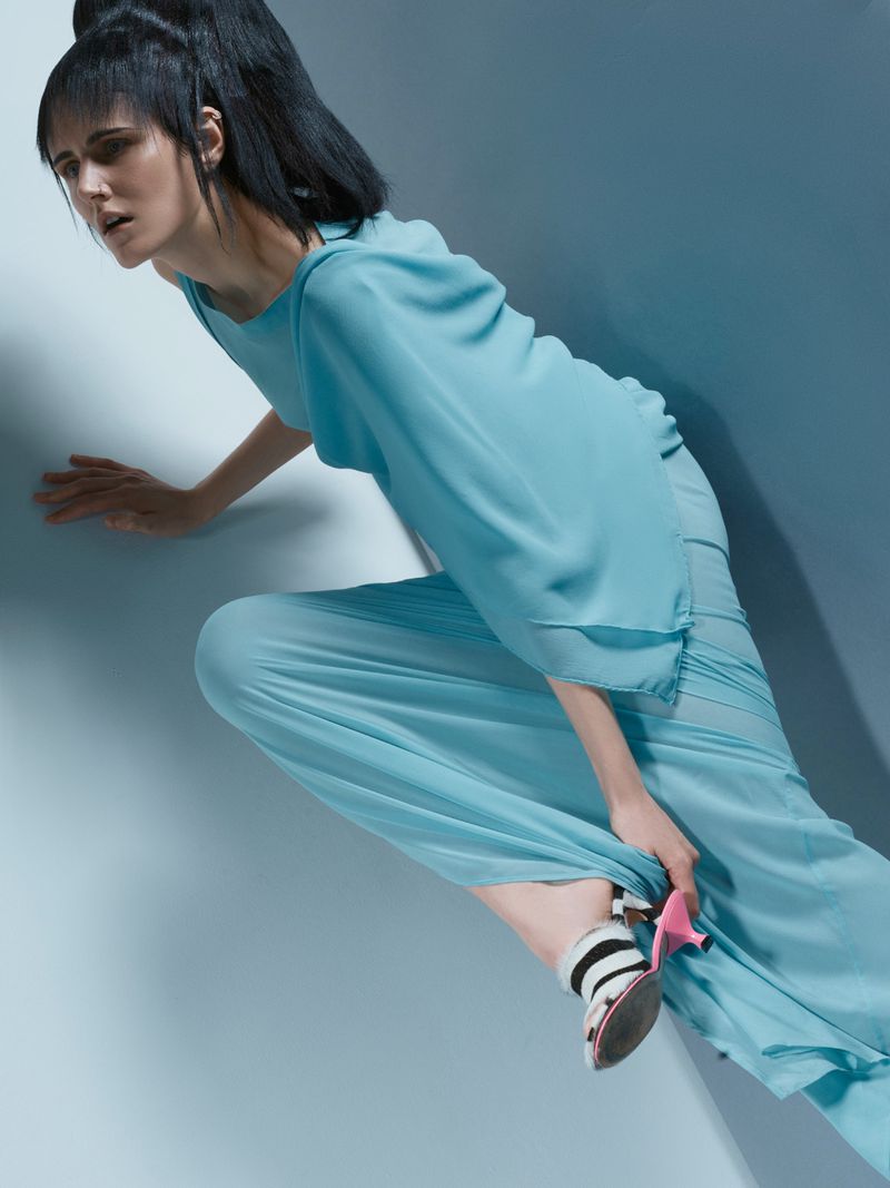 Elegant adult female in a flowing turquoise gown and zebra-print heeled shoes, photographed against a gradient blue studio backdrop.