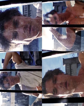 Adult man's face with a sad expression, partially shirtless, reflected in a multi-pane window with a cityscape background on a sunny day.