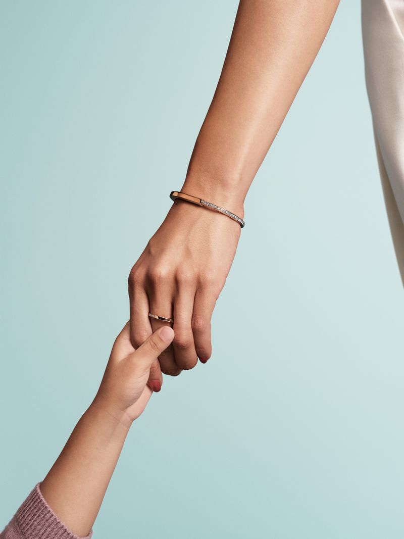 Close-up of adult and child hands touching against a blue background, emphasizing connection and the delicate skin textures.