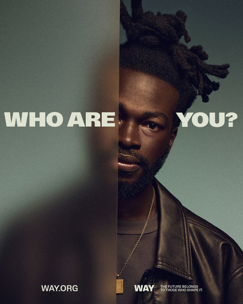 Portrait of a Black male with dreadlocks wearing a leather jacket and gold chain against a dual-tone background with the text, 'Who are you?'