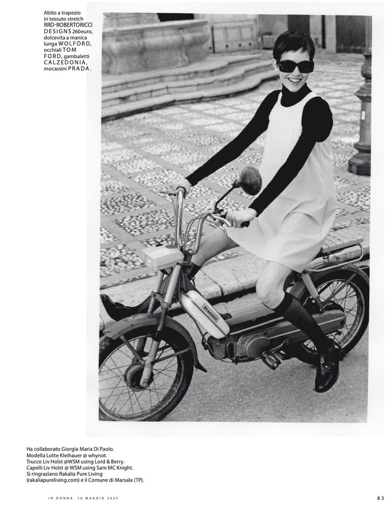 A woman in a vintage dress and sunglasses rides a moped on a patterned sidewalk in a black and white editorial fashion photograph.