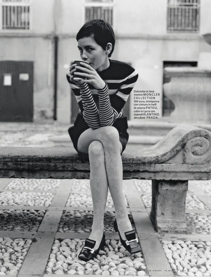 Model Lotte Kleihauer seated on a stone bench in a striped sweater drinking from a cup, photographed by Federico Sorrentino.
