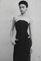 Model wearing a black strapless top against a textured wall for the Aura project photographed by Darren Mcdonald.