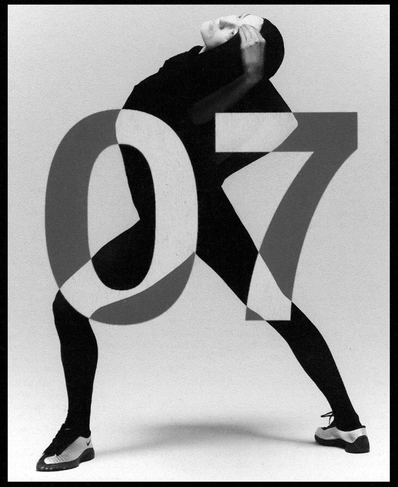 Artful studio portrait of a slender person in a black catsuit, posed behind and partially obscured by superimposed gray-scale number '07'.