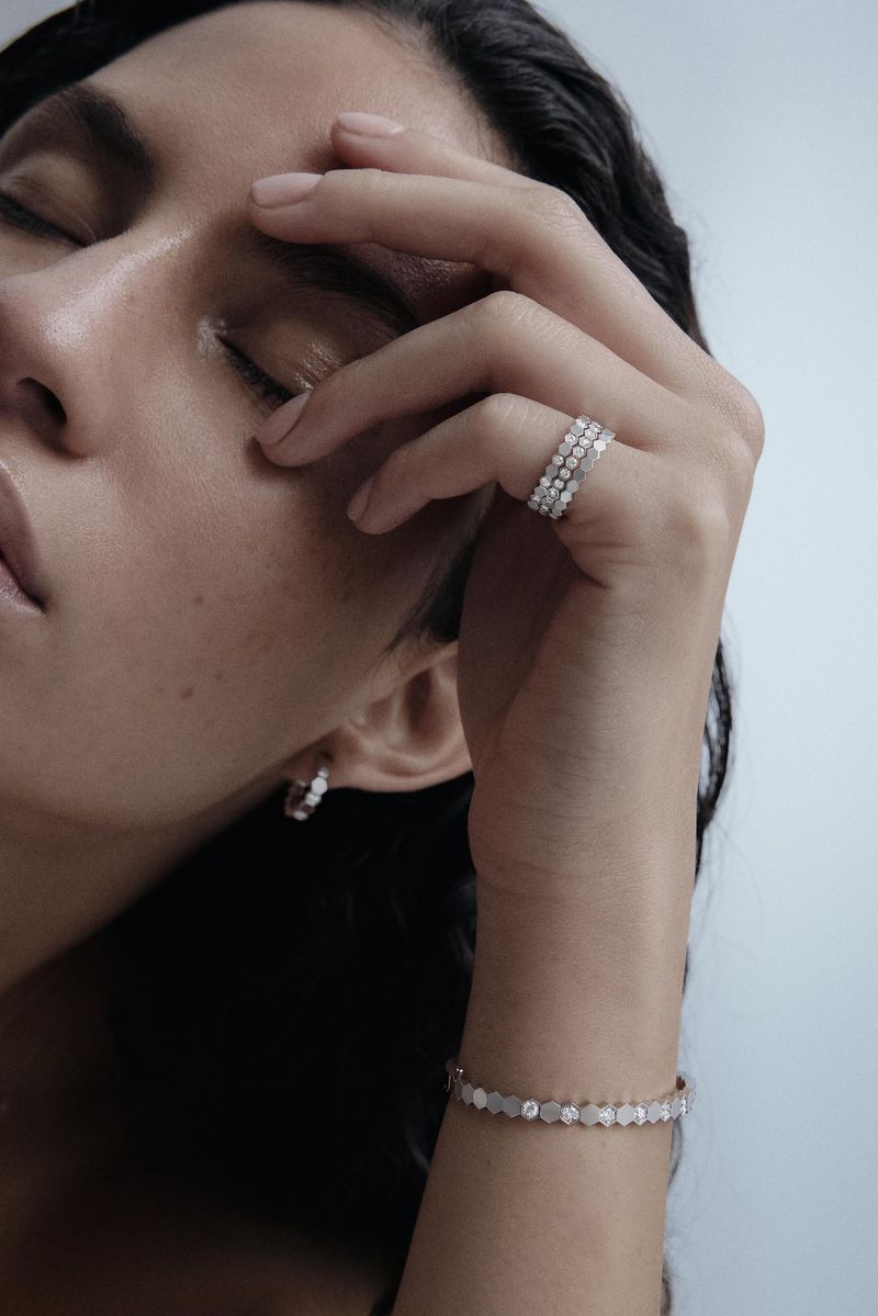 Close-up of a woman with her eyes closed wearing a diamond ring and bracelet in a softly lit indoor environment. Beauty shot.