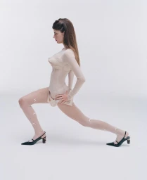 Profile view of a model in a nude-toned long-sleeve top and patterned tights with slingback heels against a white studio seamless.