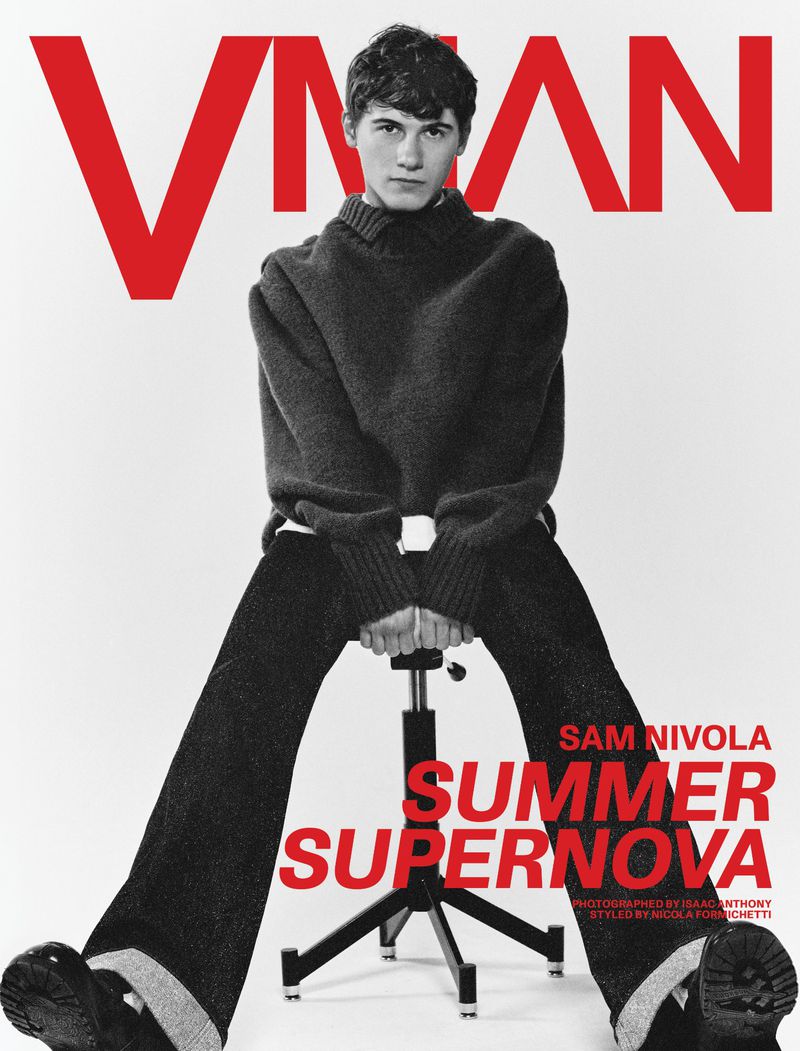 Magazine cover featuring a young man seated on a stool, wearing a dark sweater and pants against a white backdrop with red text.