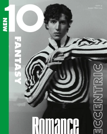 Magazine cover featuring a stylish young man with curly hair in a black and white patterned sweater and black pants.