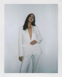 Model Irina Shayk wearing a white suit against a plain background