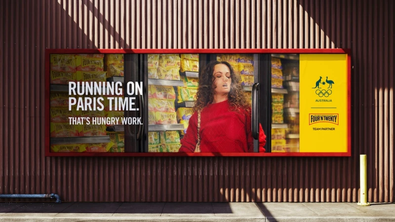 Outdoor advertisement featuring a woman in red by a cooler full of snacks, promoting Four'N Twenty with the Australian Olympic logo.