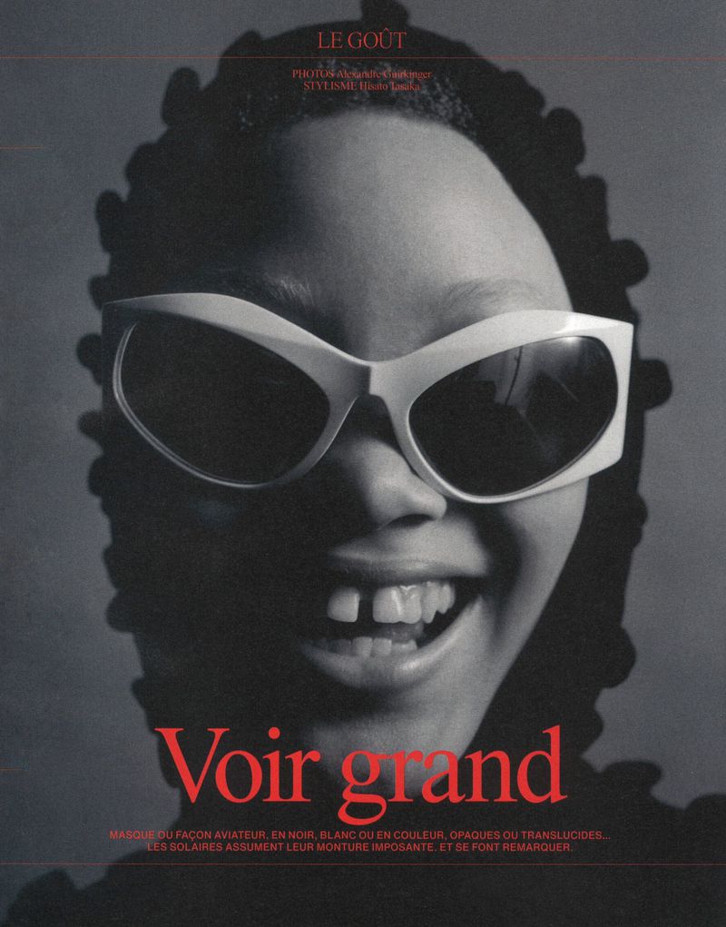Portrait of a smiling Black woman wearing oversized white sunglasses. Headshot with a red text overlay on a dark grey background.