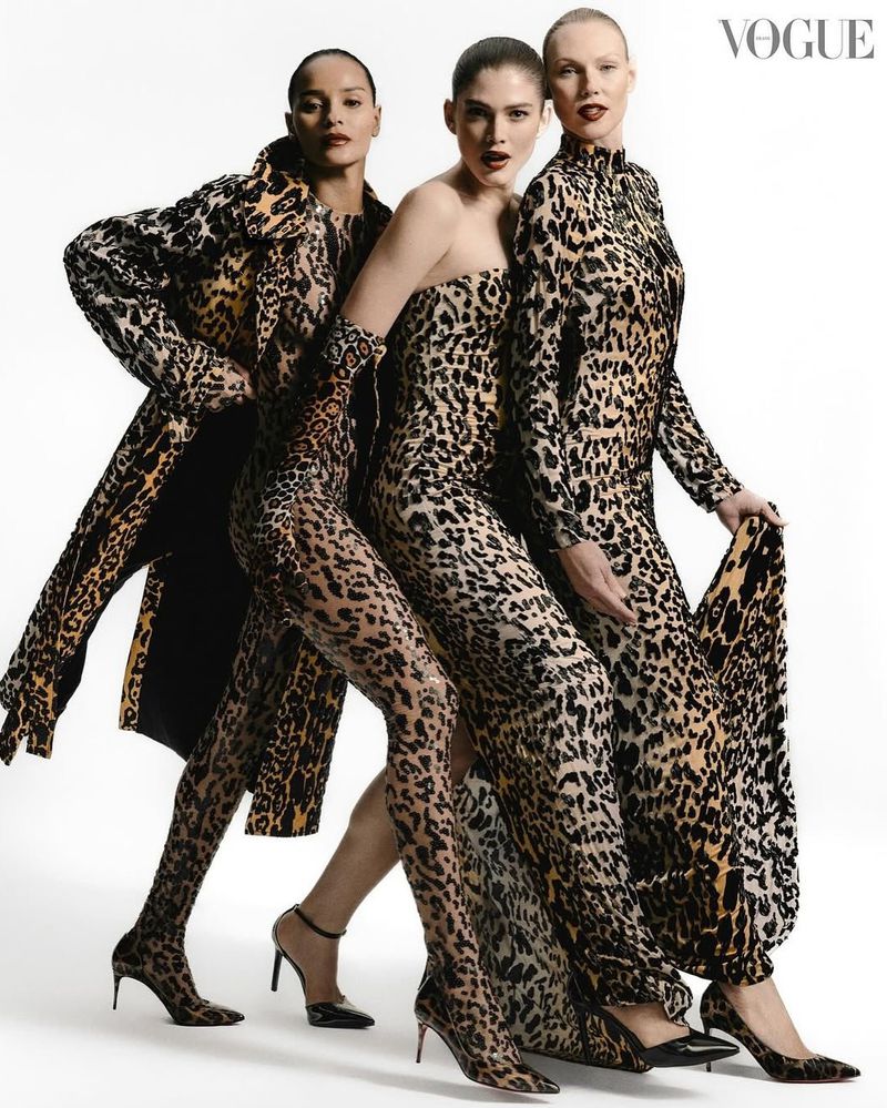 Three fashion models pose in a studio wearing head-to-toe matching leopard print dresses and a coat in front of a white background.