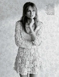 Model Klara Kristin in a white lace dress standing against a patterned wallpaper background for Elle France