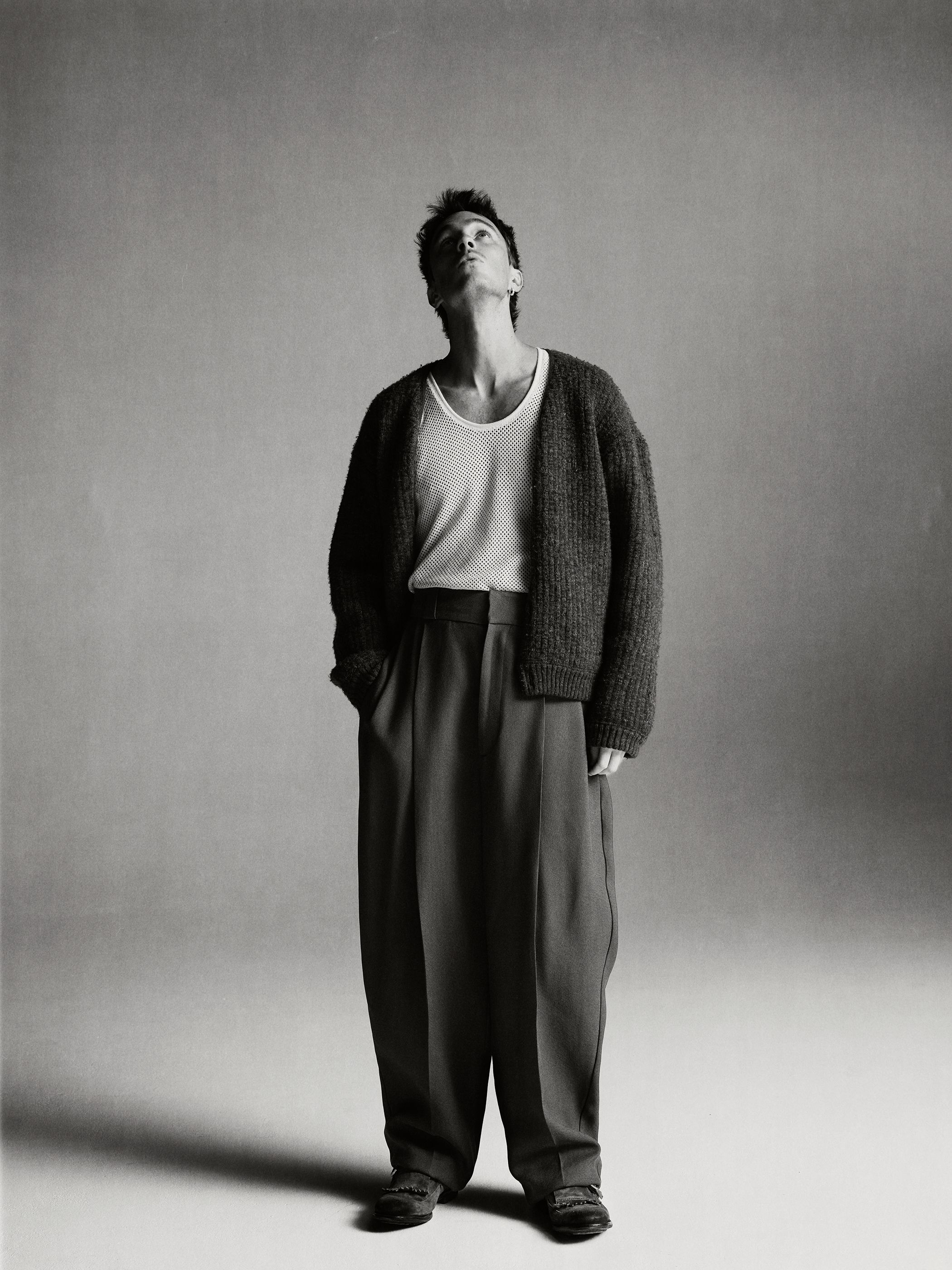 Drew Starkey standing in a knitted cardigan and trousers against a neutral background for Esquire Australia.