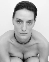 Portrait of a woman wearing a beaded necklace against a plain white background for Completedworks