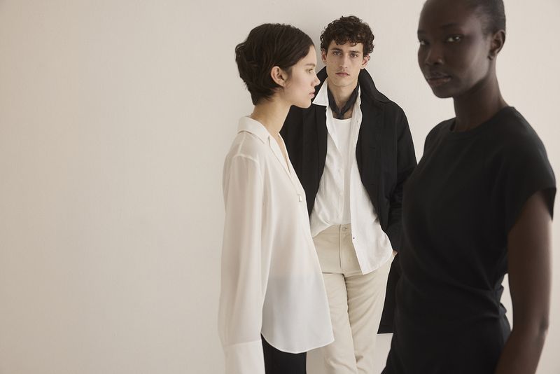 Three fashion models pose in a studio against a white background, showcasing modern apparel and minimalist style in a clean, well-lit setting.