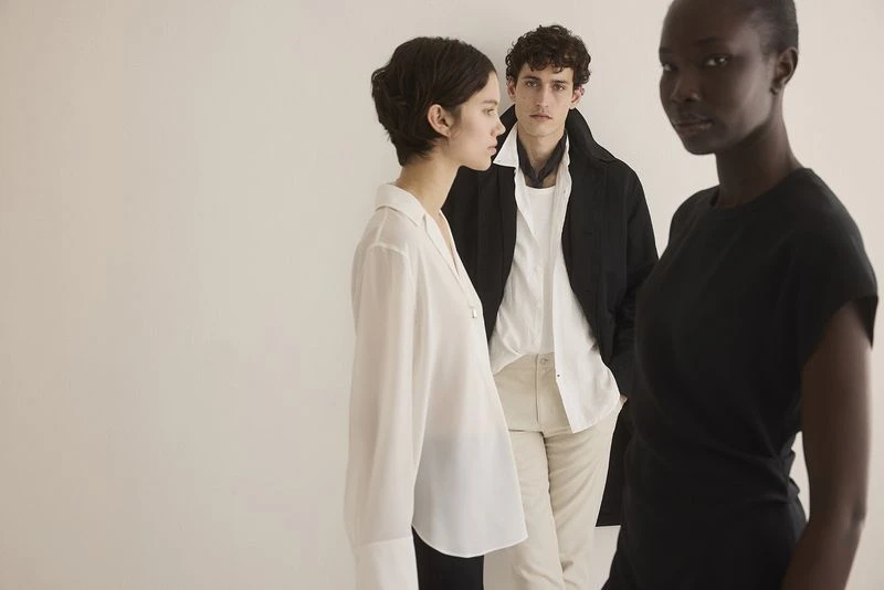Three fashion models pose in a studio against a white background, showcasing modern apparel and minimalist style in a clean, well-lit setting.