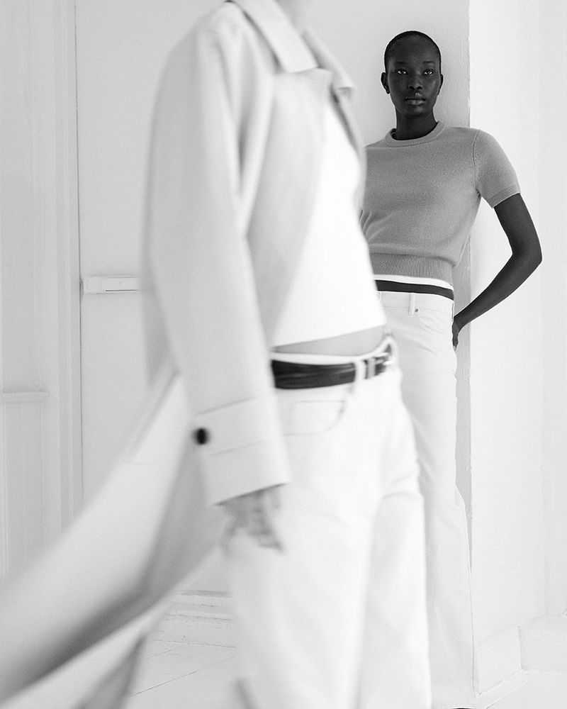 Two fashion models in a minimalist setting wearing casual outfits in a black and white studio shot with a shallow depth of field.