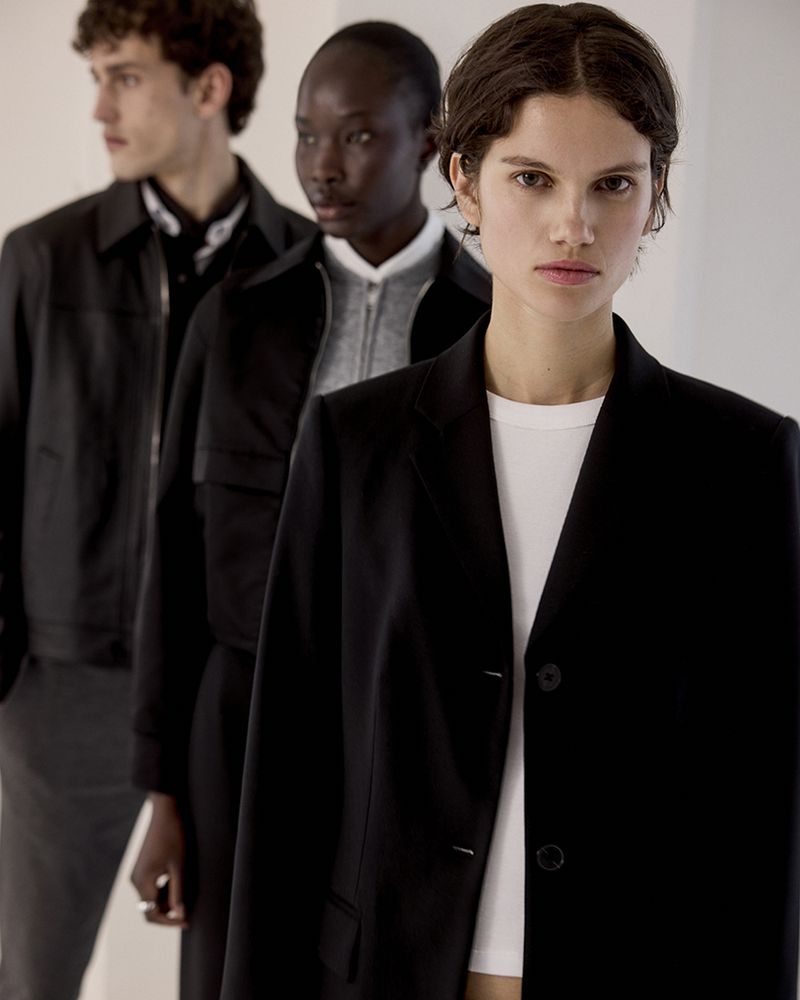 Fashion editorial featuring a diverse group of models in stylish jackets against a neutral backdrop in a studio setting.