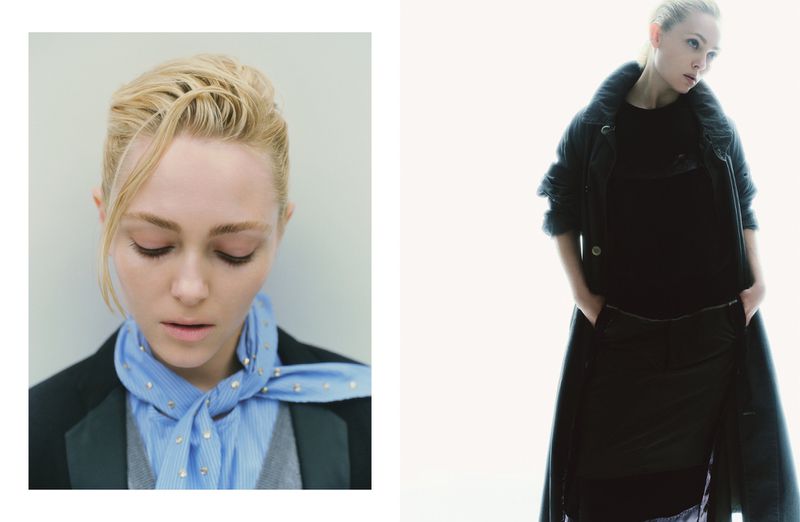 Fashion portrait of a fair-skinned adult woman with blond hair and blue eyes, wearing a striped shirt, scarf, and jacket on white backdrop.
