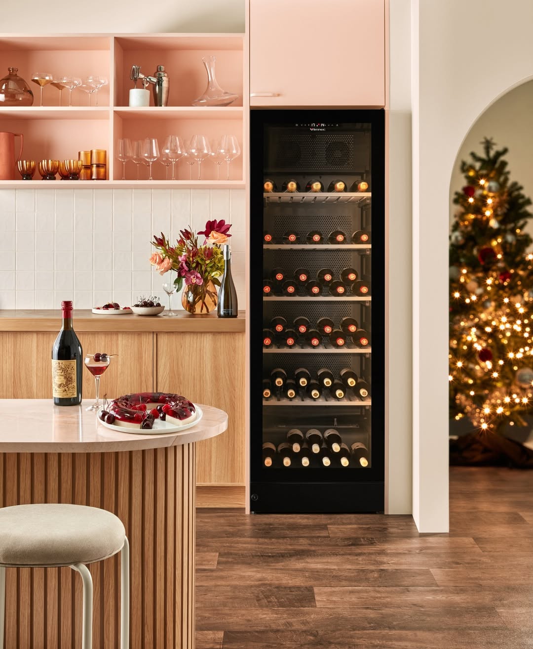 Festive interior with wine refrigerator, drinks, and Christmas tree, featuring wood textures, pastel colors, and a warm, inviting ambiance.