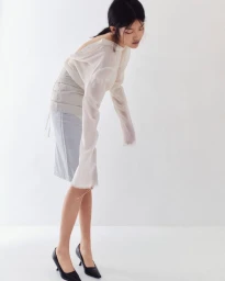 Model Yuzhu Huang wearing sheer long-sleeve top and pale skirt against white background for Tide Magazine Issue 6 editorial
