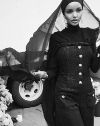 Model Halima Aden wearing a black buttoned dress and sheer veil for Vogue Arabia Modest Fashion project